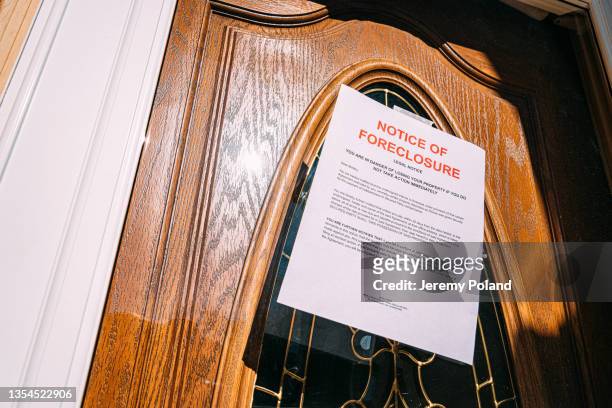 paper foreclosure notice taped to the glass front door of a home in a residential suburban neighborhood - information sign stock pictures, royalty-free photos & images