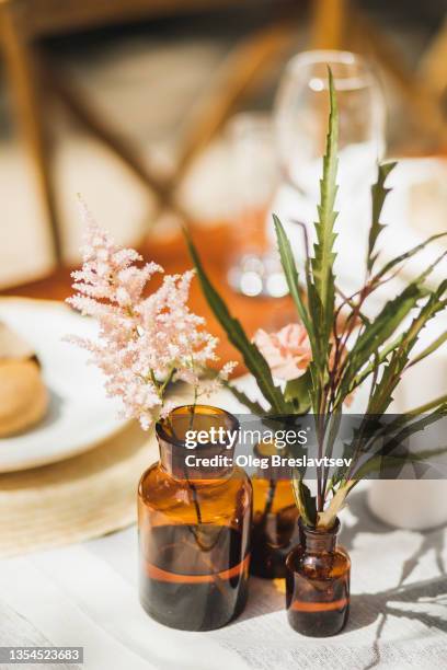 served table with trendy wedding decorations with dry and fresh flowers in brown bottles - eucalyptus stock pictures, royalty-free photos & images