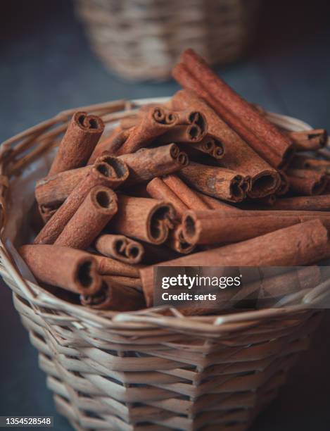 bunch of aromatic cinnamon sticks in a wooden basket - cassia bark stock pictures, royalty-free photos & images