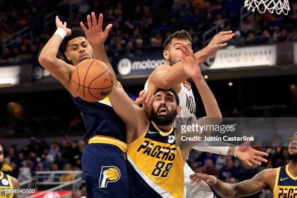 Goga Bitadze and Jeremy Lamb of the Indiana Pacers fight for the ball against Willy Hernangomez of the New Orleans Pelicans during the fourth quarter...