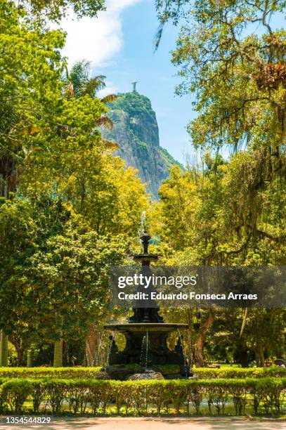 an old fountain and the statue of christ the redeemer on the background on top of the corcovado mountain - christ the redeemer rio stock-fotos und bilder