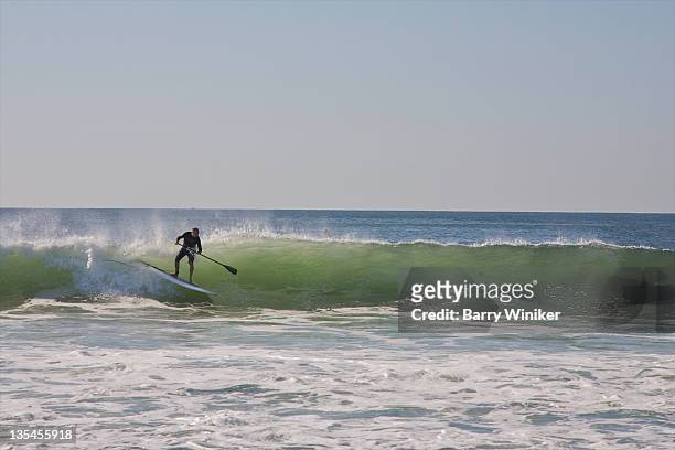 man on paddle board riding a wave. - insel long island stock-fotos und bilder