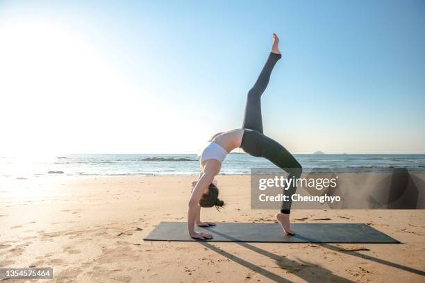 a woman practicing yoga by the sea - sunrise yoga foto e immagini stock