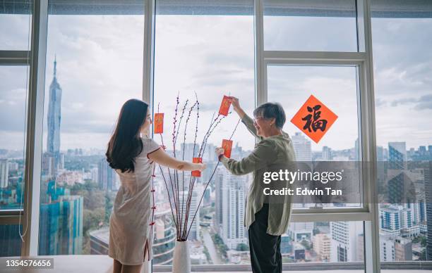 chinese new year senior woman and her daughter decorating house living room with pussy willow and red packet ang pao decoration preparing for family reunion - pussy willow stock pictures, royalty-free photos & images