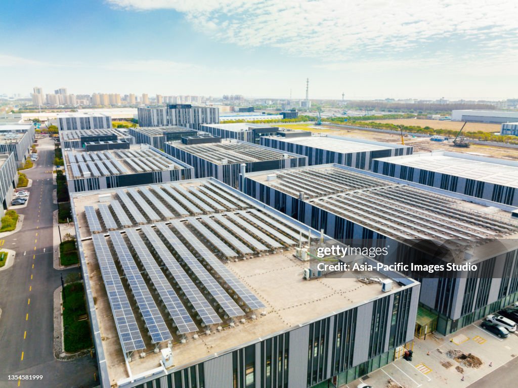Aerial view of solar panels on factory roof. Blue shiny solar photo voltaic panels system product.