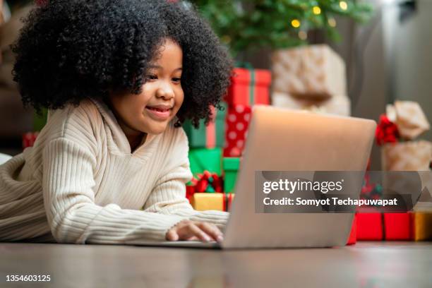 afro female child rising hand up want to answer question from online teacher,african american female child concentrate focus study online on laptop internet in living room at home,girl spending time with laptop in christmas holiday vacation - homegirl stock pictures, royalty-free photos & images
