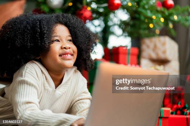 afro female child rising hand up want to answer question from online teacher,african american female child concentrate focus study online on laptop internet in living room at home,girl spending time with laptop in christmas holiday vacation - homegirl stock pictures, royalty-free photos & images