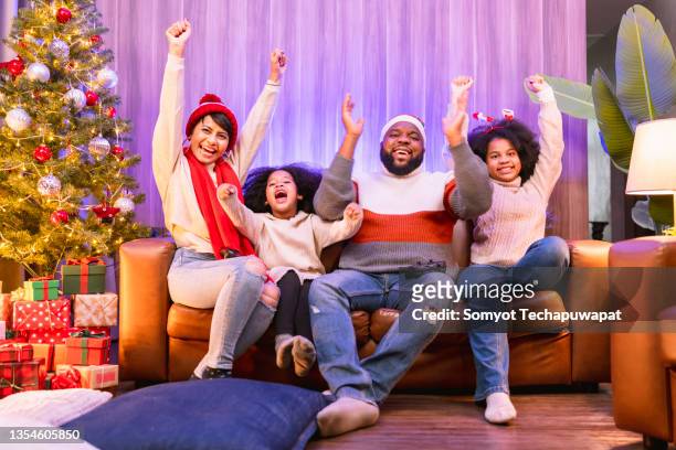 african american family happiness cheering embracing celebrating goal while watching sports on tv at home ,family spending time together at christmas holiday vacation - sports round stock-fotos und bilder