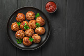 Meatballs with basil and tomato sauce on a black background