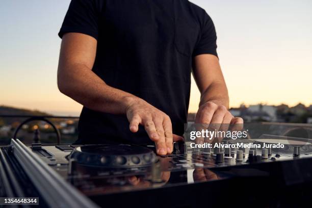 unrecognizable male dj hands playing music in a session with a mixer at a sunset party on a terrace. - dj stockfoto's en -beelden