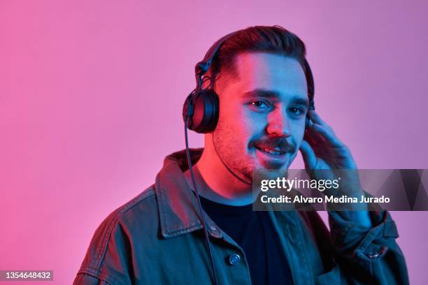 young male dj playing music in a session with red and blue lighting backgrounds. - dance music stock pictures, royalty-free photos & images