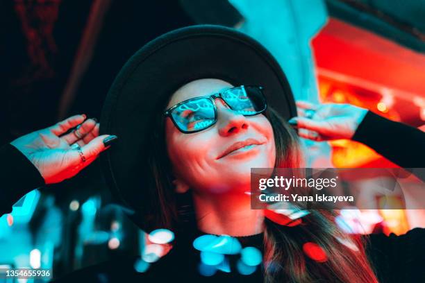 young pretty hipster woman in glasses and hat is dancing in neon lights - laterne stock-fotos und bilder