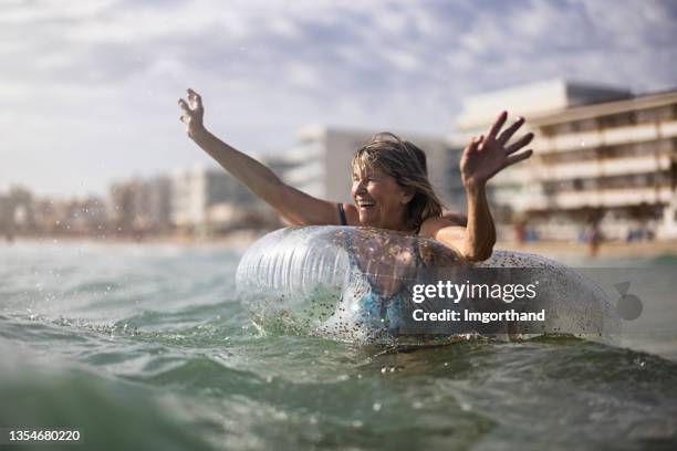 happy senior woman enjoying floating ring in the sea - nice old town stock pictures, royalty-free photos & images