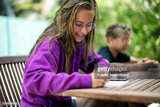 teenager sitzen am hinterhoftisch und schreiben postkarten - postkarte stock-fotos und bilder