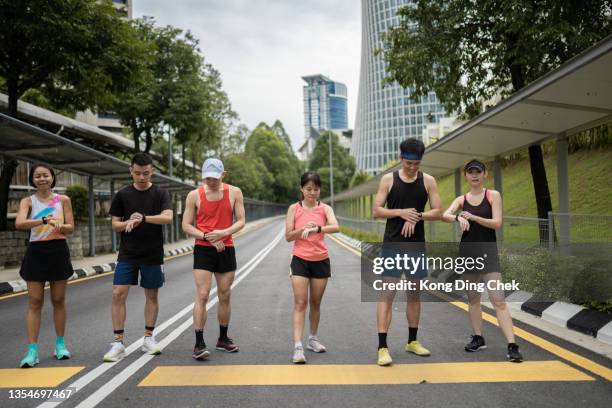 asiatische chinesische athleten, die sich aneinanderreihen, beginnen mit dem timing der fitness-tracer-smartwatch vor dem laufen. - mixed race man stock-fotos und bilder