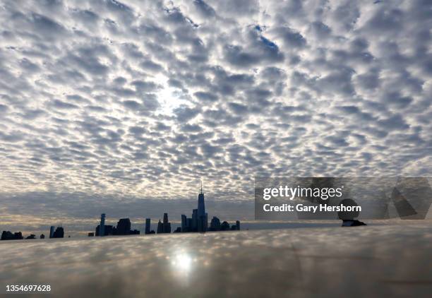 Clouds pass over lower Manhattan and One World Trade Center as the sun rises on November 21 as seen from Hoboken, New Jersey.