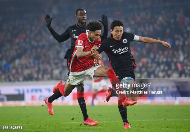 Kevin Schade of SC Freiburg battles for possession with Makoto Hasebe of Eintracht Frankfurt during the Bundesliga match between Sport-Club Freiburg...
