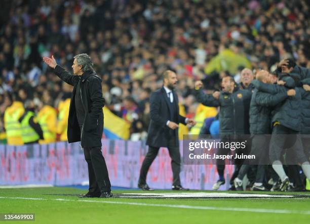 Head coach Jose Mourinho of Real Madrid reacts as head coach Josep Guardiola and players of FC Barcelona celebrate their sides third goal during the...