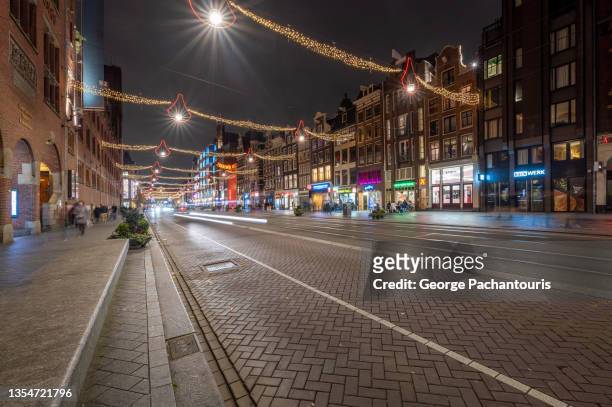 damrak road in amsterdam with christmas decorations - amsterdam noel stock-fotos und bilder