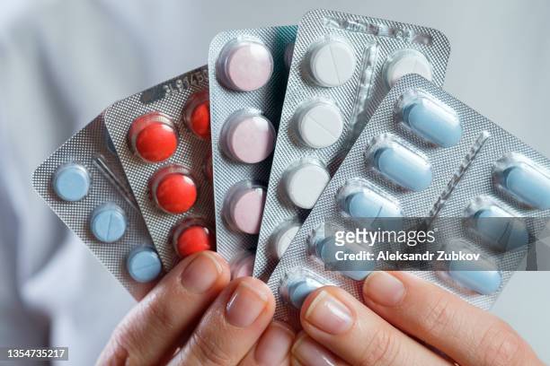 white and colored capsules and tablets in the hand of a girl or woman. taking vitamins, painkillers, medications, food additives. the concept of prevention and treatment of diseases, health care and medicine. pregnancy planning, filling in deficits. - slaappil stockfoto's en -beelden