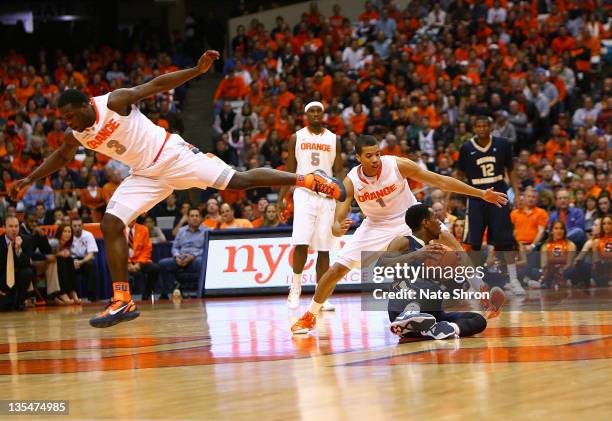 Dion Waiters of the Syracuse Orange trips over teammate Michael Carter-Williams as he guards Tony Talor of the George Washington Colonials as he...