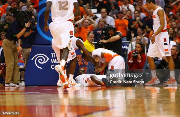 Dion Waiters of the Syracuse Orange smiles as he is picked up by his teammates after falling during the game against the George Washington Colonials...