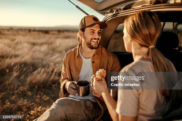 happy couple having breakfast in car trunk on field - conversation car bildbanksfoton och bilder