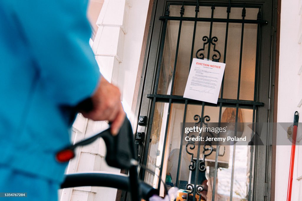Elderly Person With Walker Standing and Looking at an Eviction Notice on the Front Door of a Home