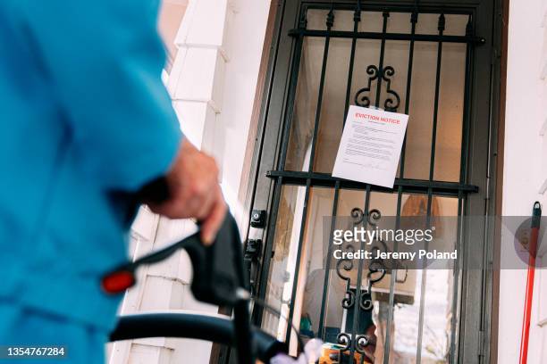 elderly person with walker standing and looking at an eviction notice on the front door of a home - vräkning bildbanksfoton och bilder