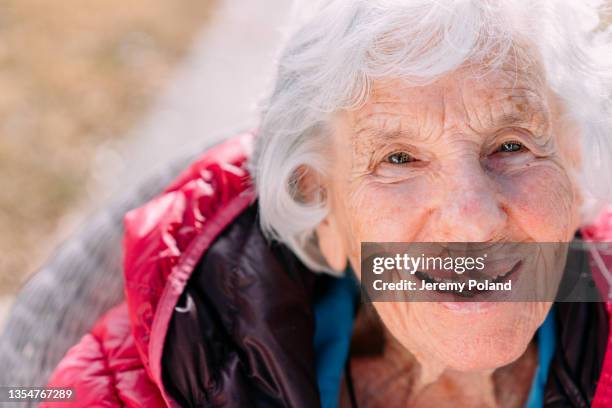 close-up shot of a cheerful 100-year-old elderly senior caucasian woman sitting outdoors in the winter - 101 stockfoto's en -beelden