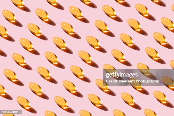 pop art pattern fish oil capsules with omega-3 vitamin d on a pink background - vitamin a stock pictures, royalty-free photos & images