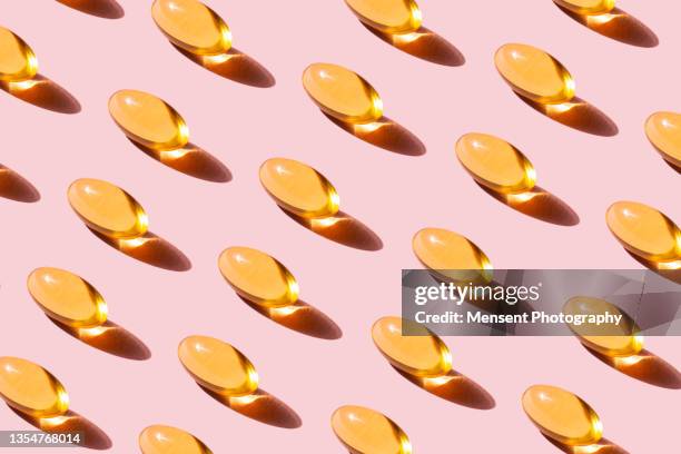 pattern of yellow fish oil capsules with omega-3 repetition on pink background - ビタミンd ストックフォトと画像