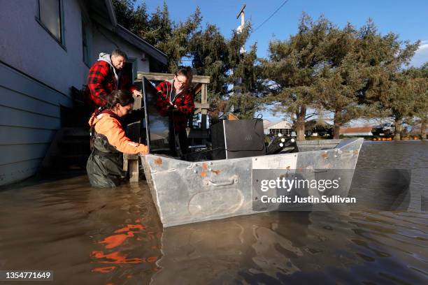 Dennis Penner and his daughters Nakita Penner and Brenna Penner load a television into a boat as they move personal items from their flooded home on...