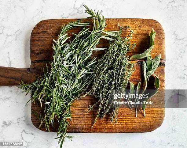 herbs (rosemary, sage, and thyme) on wooden cutting board - rosemary fotografías e imágenes de stock