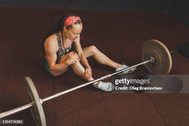 knee injury of woman lifting barbell in gym. health problem, sprain ligament, stress and pain - sports pain stock-fotos und bilder