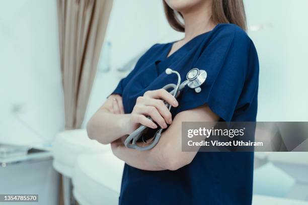 closeup of a doctor in blue uniform and holding a stethoscope in a hand standing in hospital. - suckling stock pictures, royalty-free photos & images