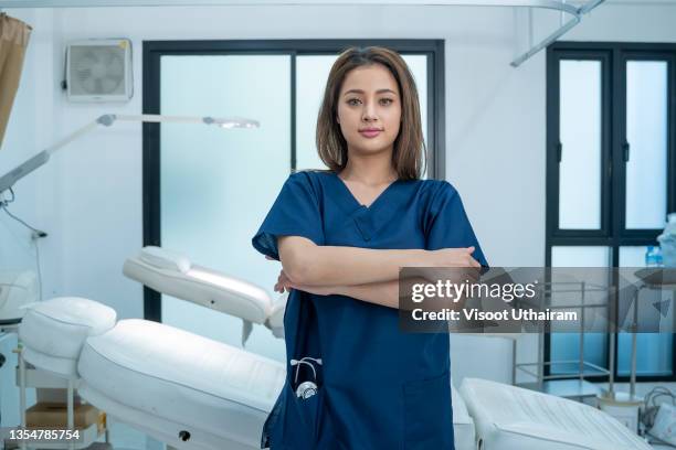 smiling female doctor in lab coat with arms crossed at hospital. - mitarbeiter lab stock-fotos und bilder