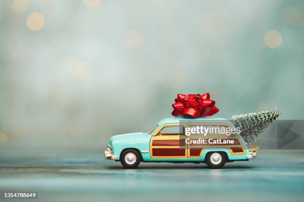 christmas background with vintage station wagon car with christmas tree in trunk and bow on rooftop - station wagon stock pictures, royalty-free photos & images