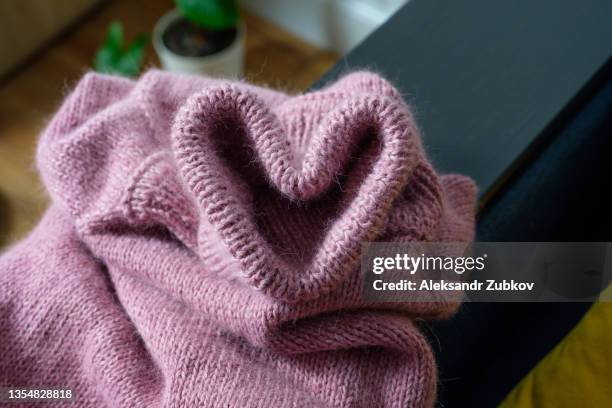 knitted sweater and metal knitting needles. a heart made of clothes. a declaration of love. skeins and threads of pink wool yarn. the concept of hobbies, creativity, needlework and handwork. valentine's day. creating clothes with your own hands. - embroidery heart stock pictures, royalty-free photos & images