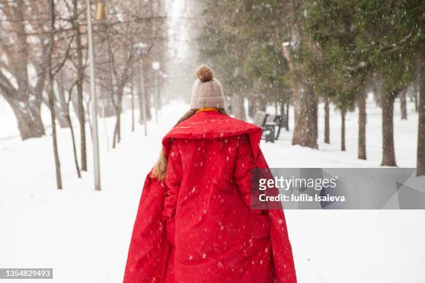 woman in outerwear walking in snowy winter park - multi colored coat stock pictures, royalty-free photos & images