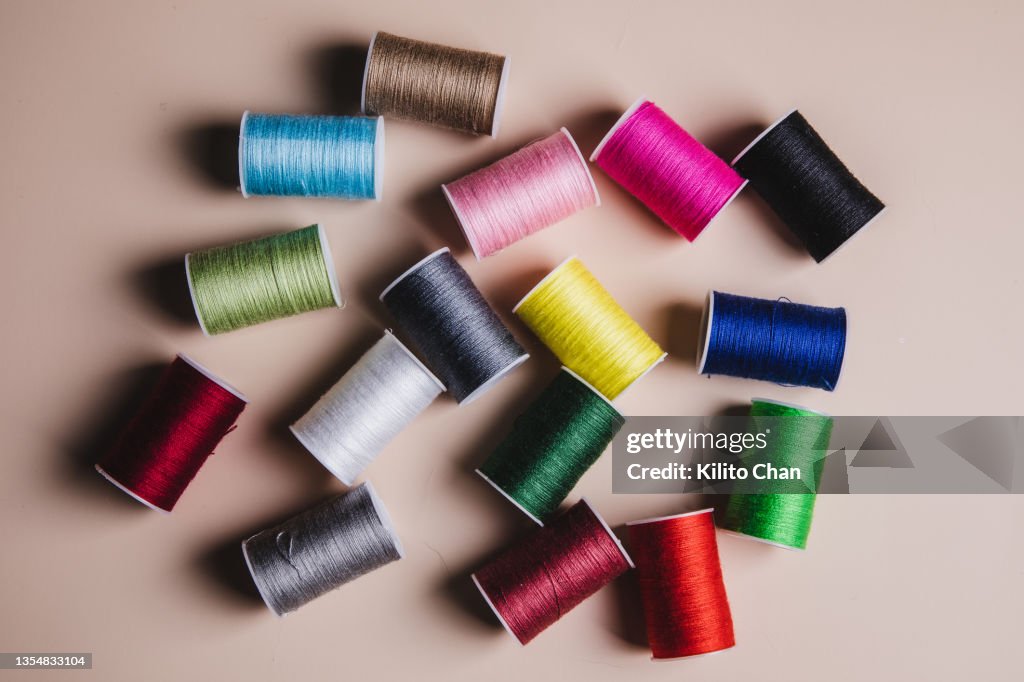 Variety of colorful sewing threads against beige background