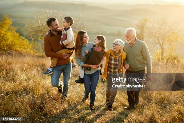 happy multi-generation family talking while taking a walk on a hill. - multi generation family stock pictures, royalty-free photos & images