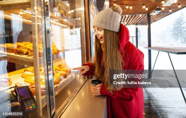 cheerful woman choosing pastries behind showcase in street cafe - finger bun stock pictures, royalty-free photos & images