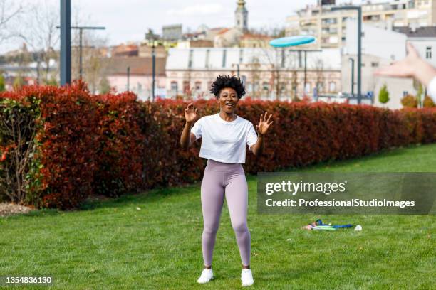 young group of multiracial friends is throwing frisbee. - throwing frisbee stock pictures, royalty-free photos & images