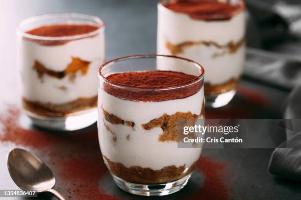 glasses of tiramisu on black background - tiramisu stock pictures, royalty-free photos & images