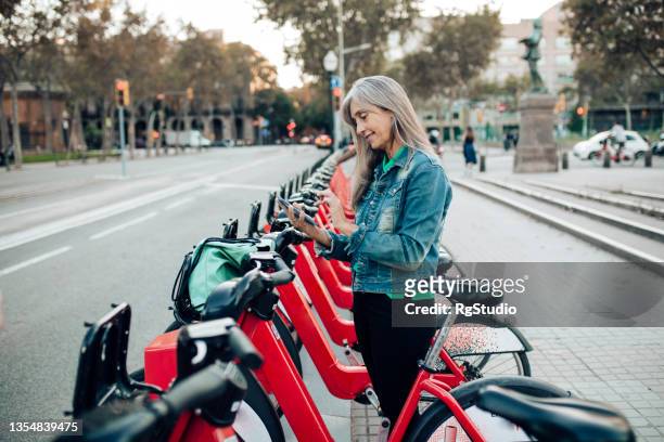 mature woman on vacation renting an e-bike - bike sharing stock pictures, royalty-free photos & images