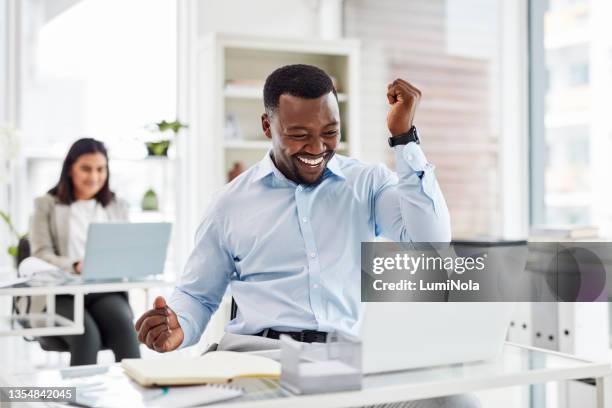 scatto di un giovane uomo d'affari che applaude mentre lavora su un laptop in un ufficio - ecstatic foto e immagini stock