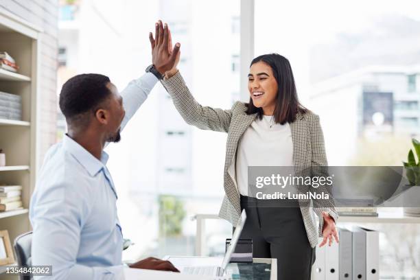 shot of two businesspeople giving each other a high five in an office - high five stockfoto's en -beelden