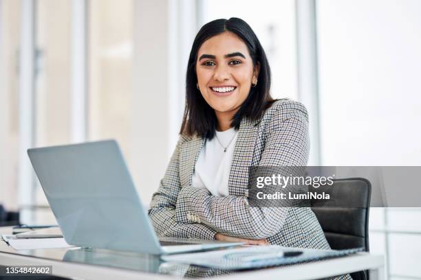 portrait of a young businesswoman working on a laptop in an office - females photos stockfoto's en -beelden