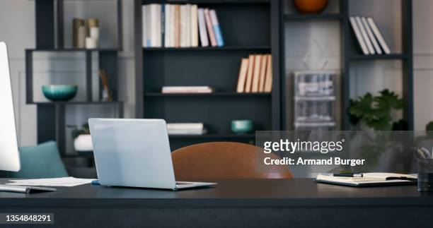 shot of a laptop in an empty office - desk office stockfoto's en -beelden